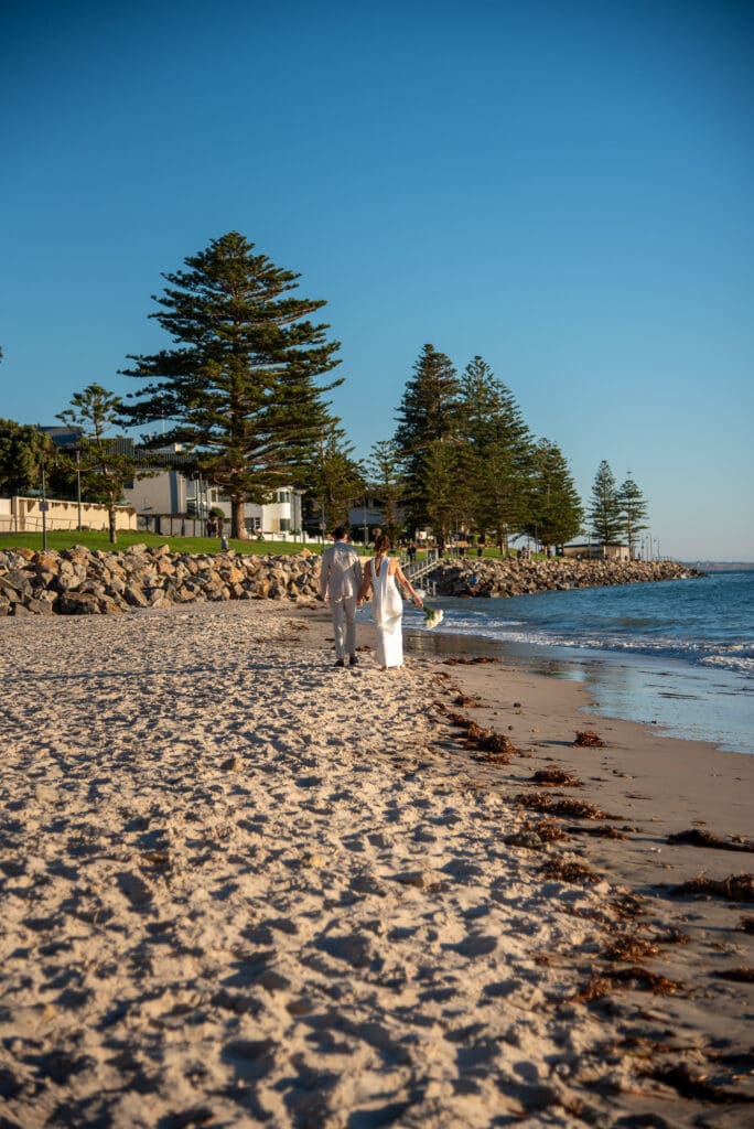 Halley and Jay wedding photo at Glenelg Beach walking along the beach